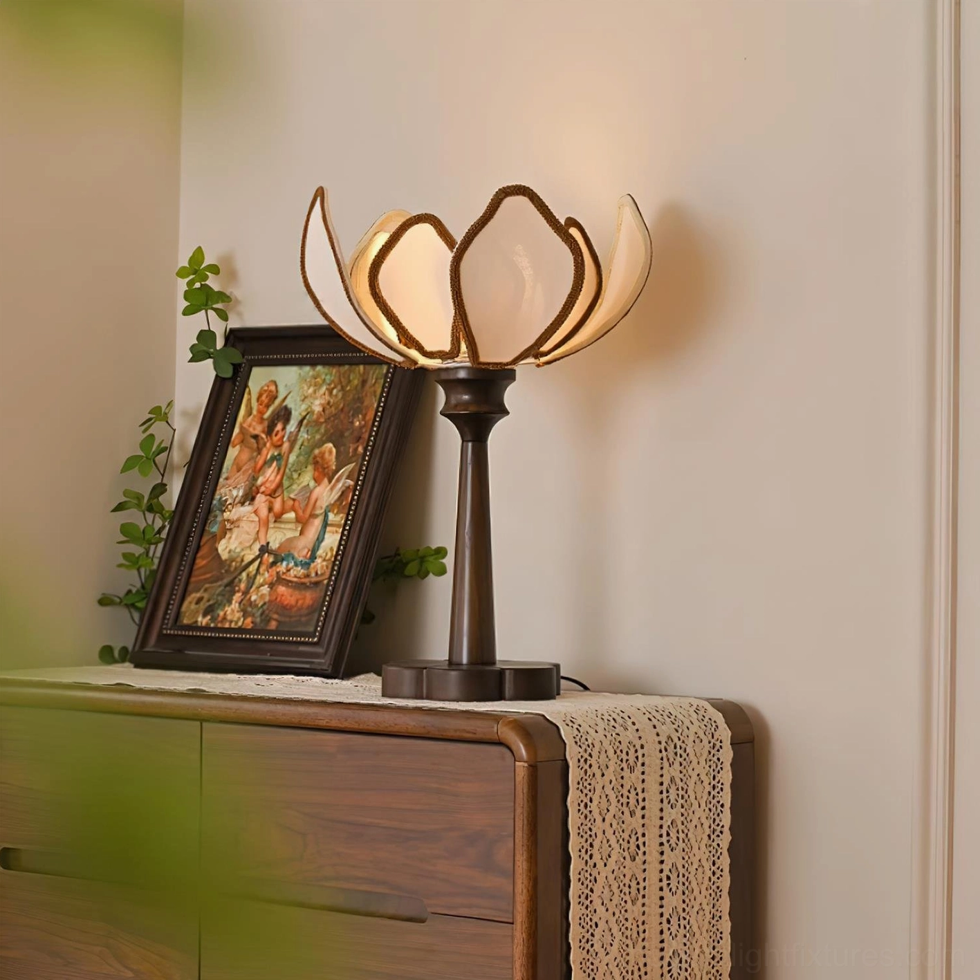 Pauline floral table lamp illuminated on dresser three-quarter view with vintage framed painting and botanical decor