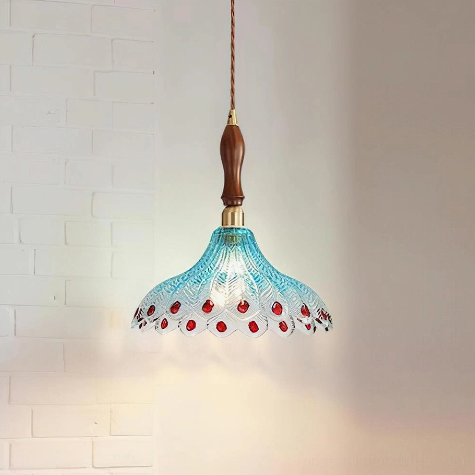 Peacock feather glass pendant lamp with blue shade and red jewel decorations against brick wall