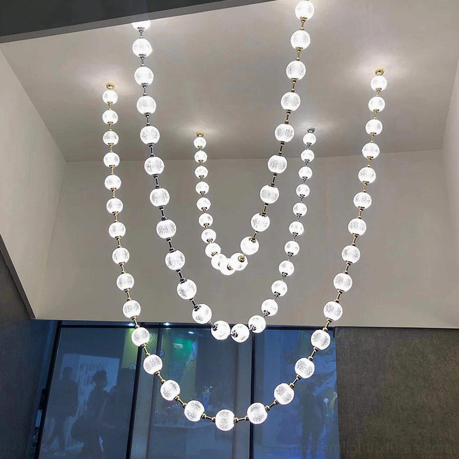 Residential pearl necklace chandelier installation above dining table creating elegant ambient lighting
