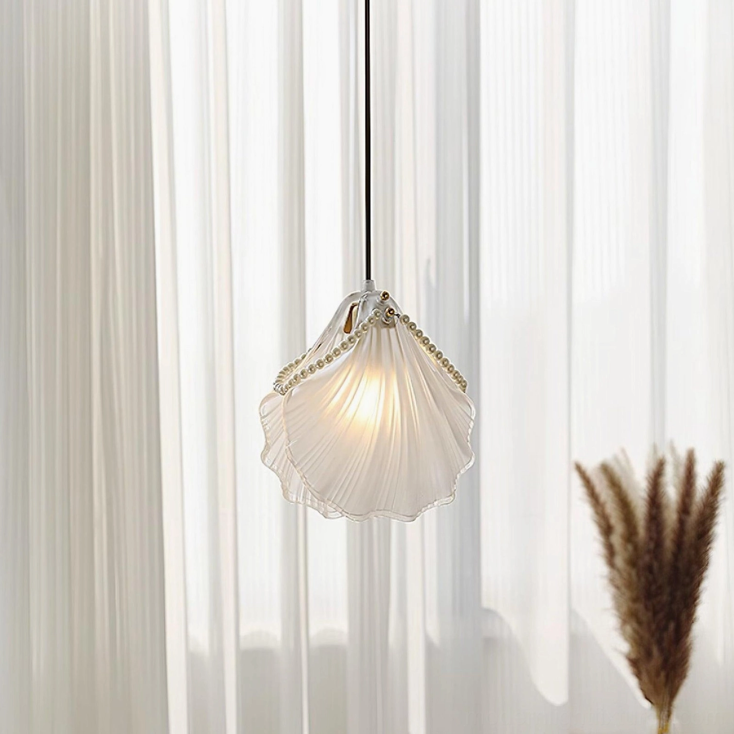 Pearl shell ceiling pendant light hanging by black cord with translucent frosted glass and gold bead trim