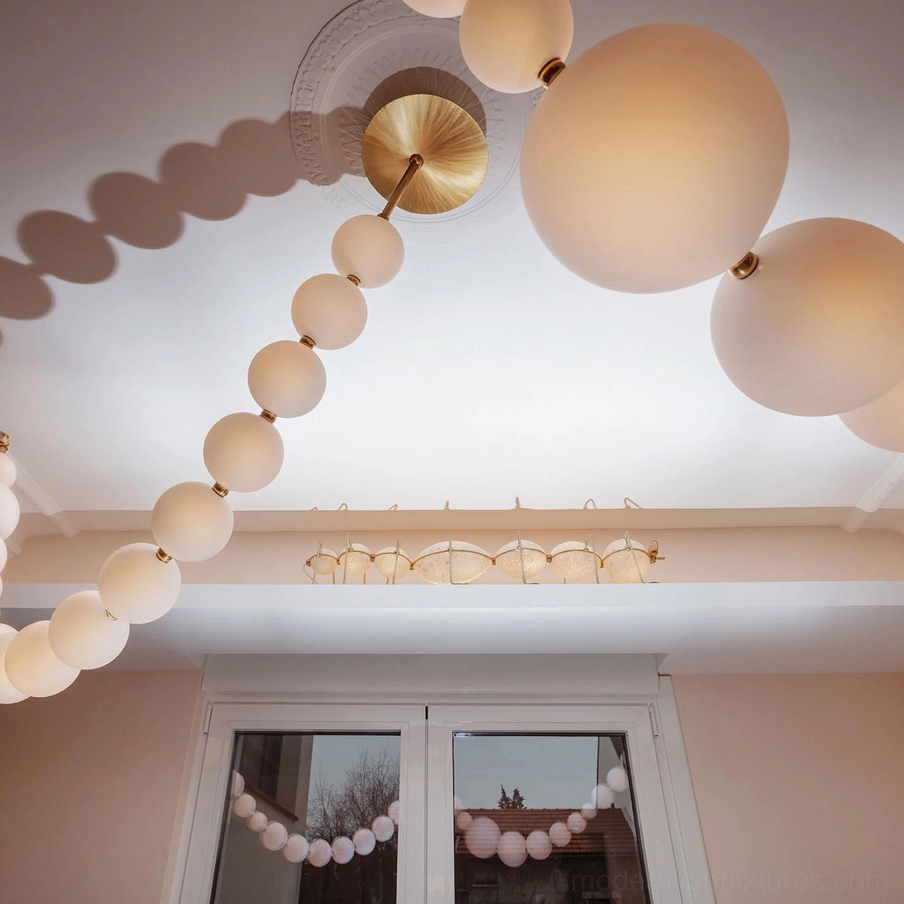 Modern pearl string chandelier lateral view displaying sphere arrangement and pendant suspension system