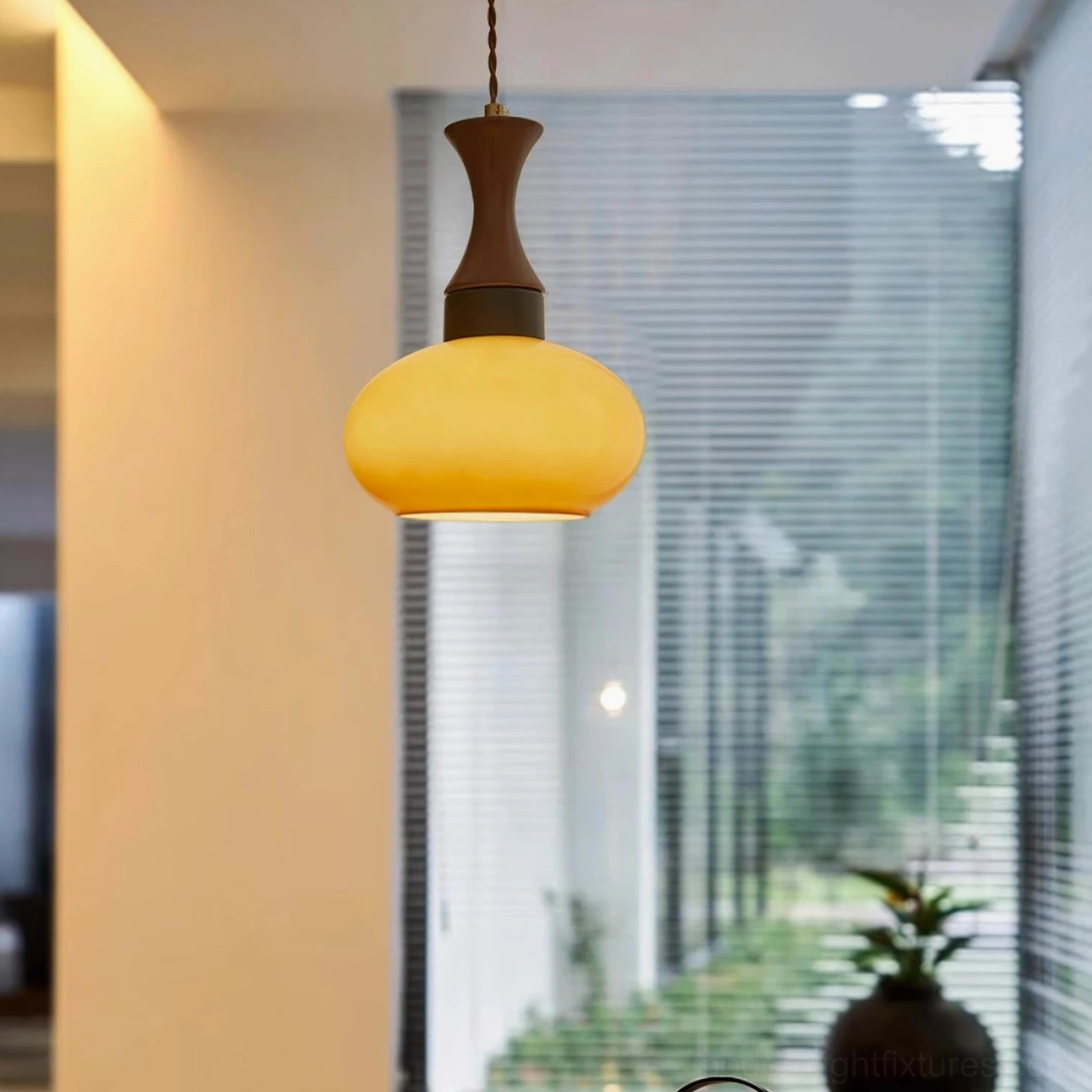 Chara plug-in pendant with yellow amber glass shade near window with wooden cabinet backdrop