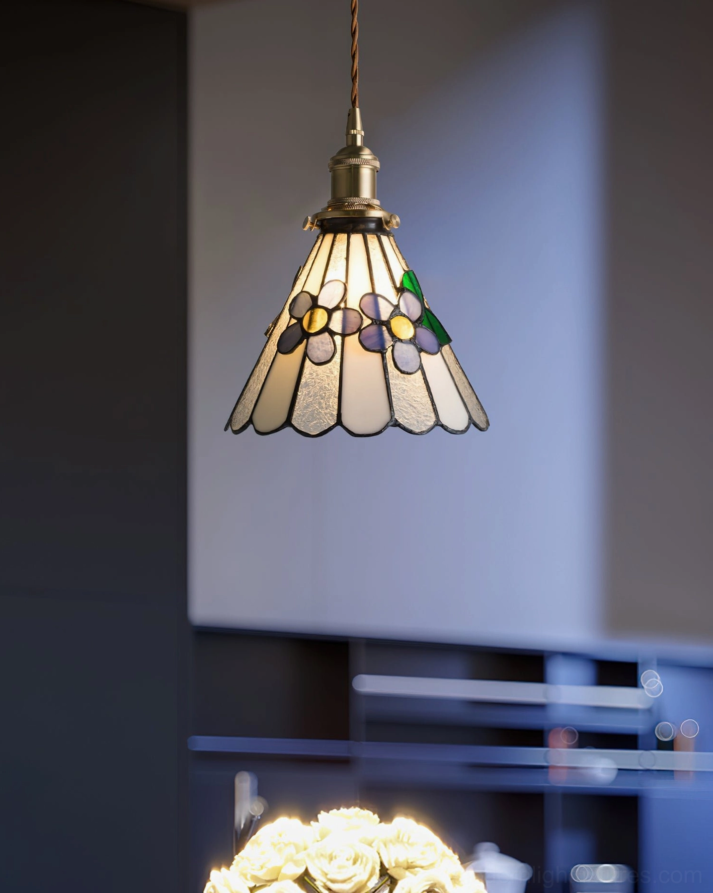 Floral stained glass pendant lamp hanging in dining space overhead view with twisted brass cord
