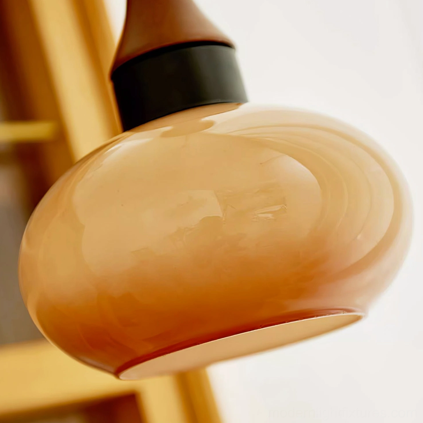 Close-up detail of glossy smooth amber glass pendant shade with metal and wood hardware