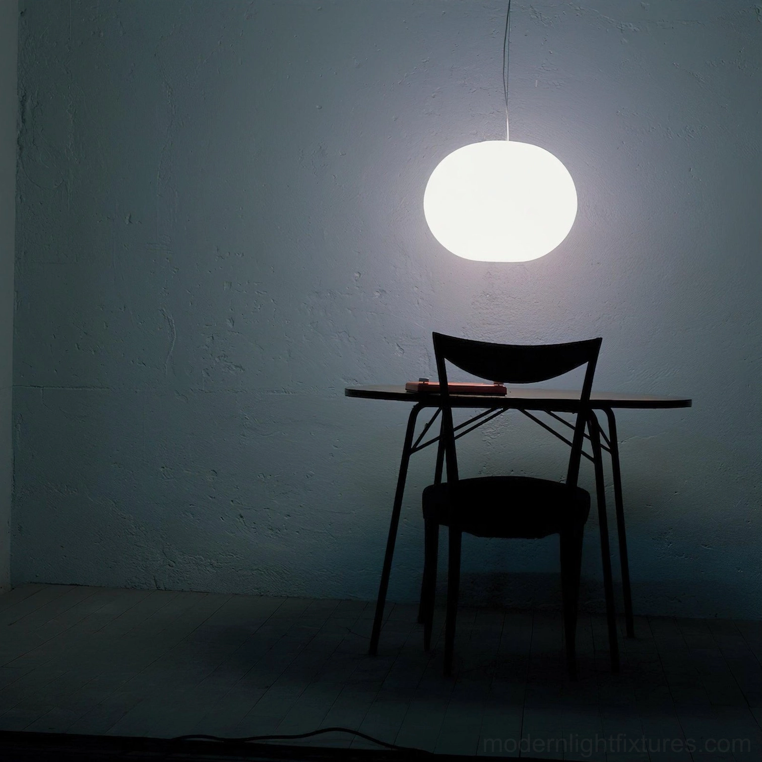 Illuminated frosted glass sphere pendant in home study corner - soft warm light in minimalist dark interior space