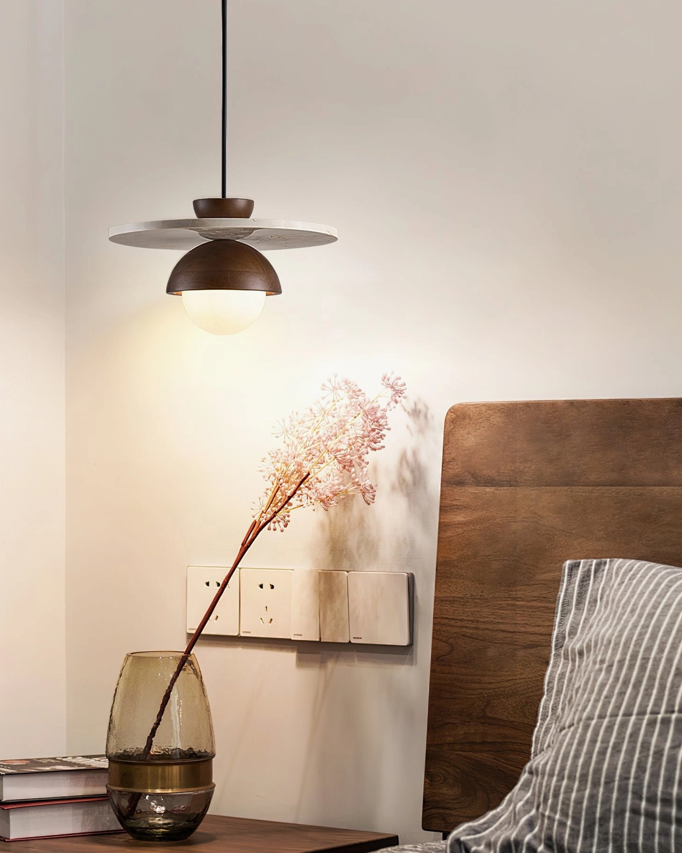 Single pendant ceiling light positioned above wooden nightstand in modern bedroom interior