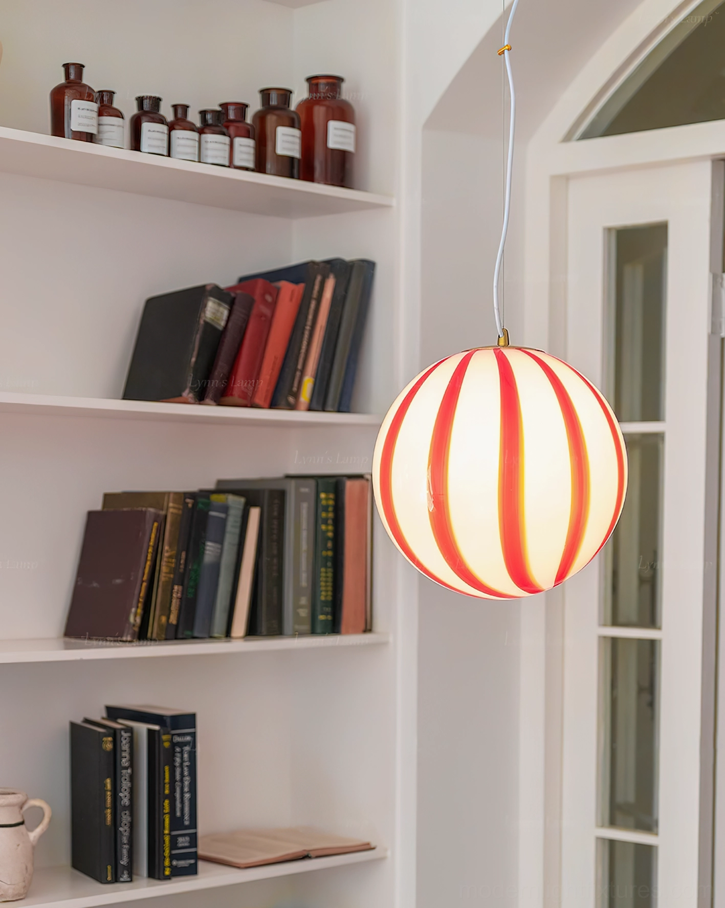 Red striped spherical pendant light illuminated in home library entryway with bookshelf decor