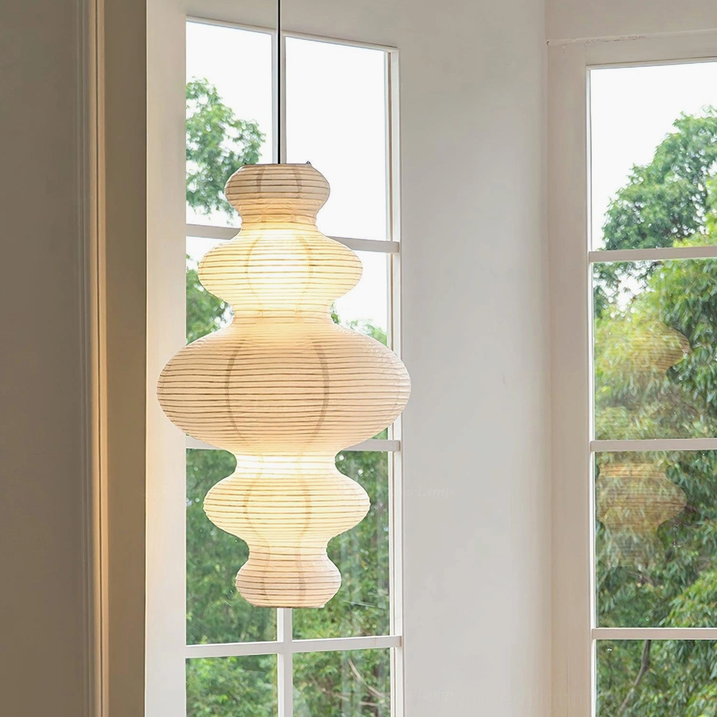Modern pendant light with warm LED bulb creating amber golden light through rice paper shade