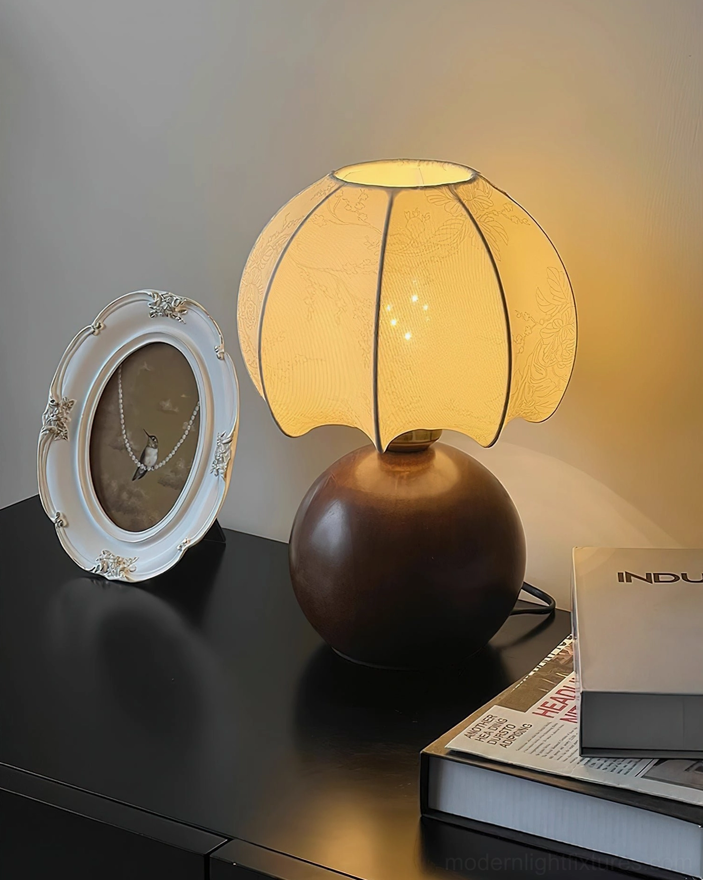 Peony bloom table lamp right three-quarter view on minimalist desk with design books