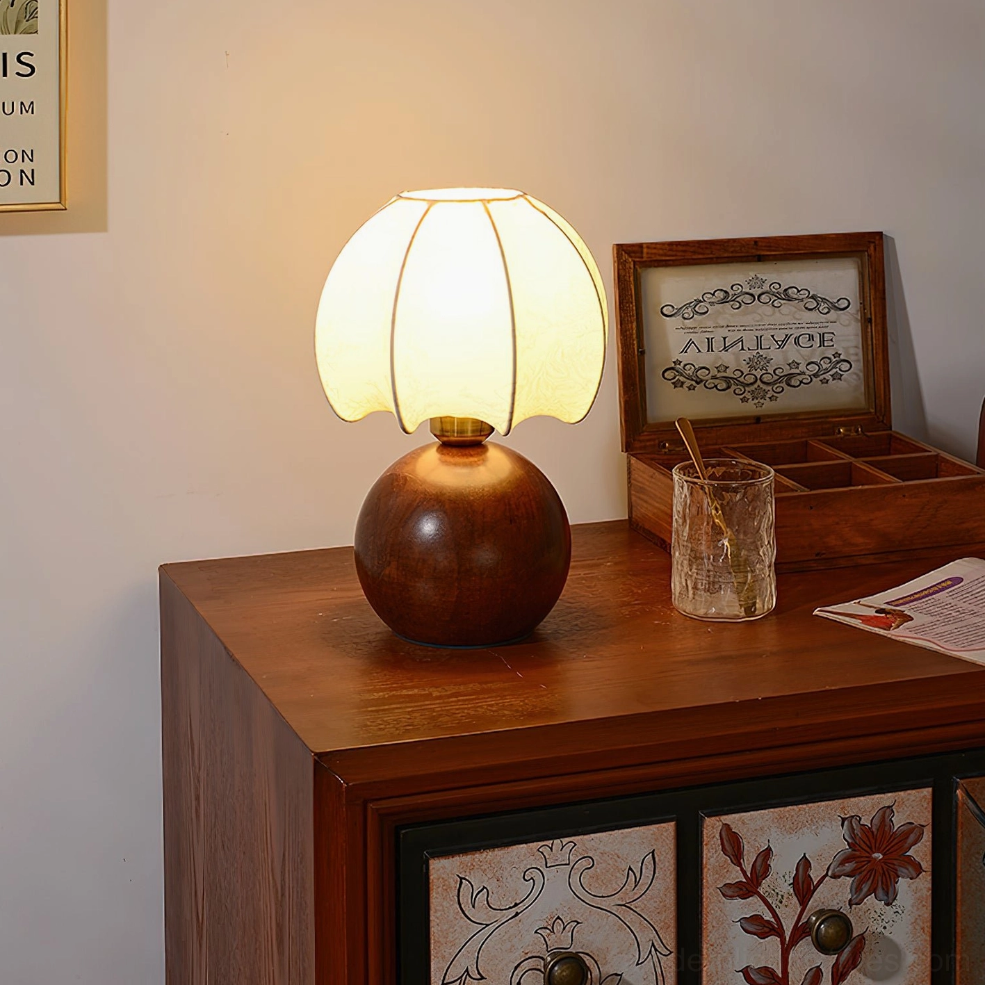 Wooden peony table lamp with glowing fabric shade styled on dresser with storage decor