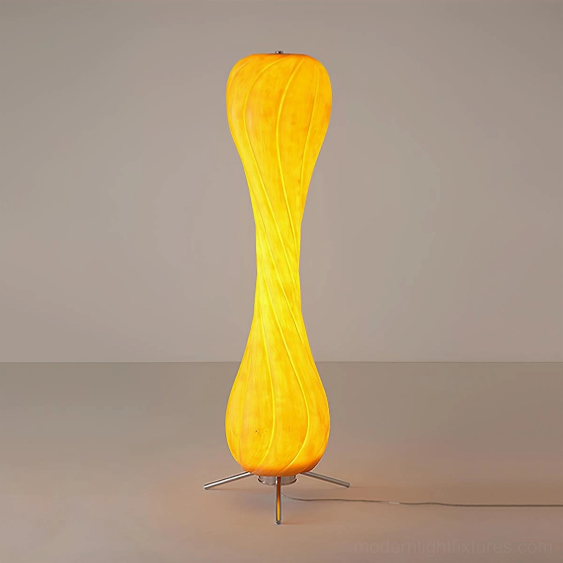 Pepperpod twisted floor lamp illuminated in studio view showing warm yellow shade and metal tripod construction