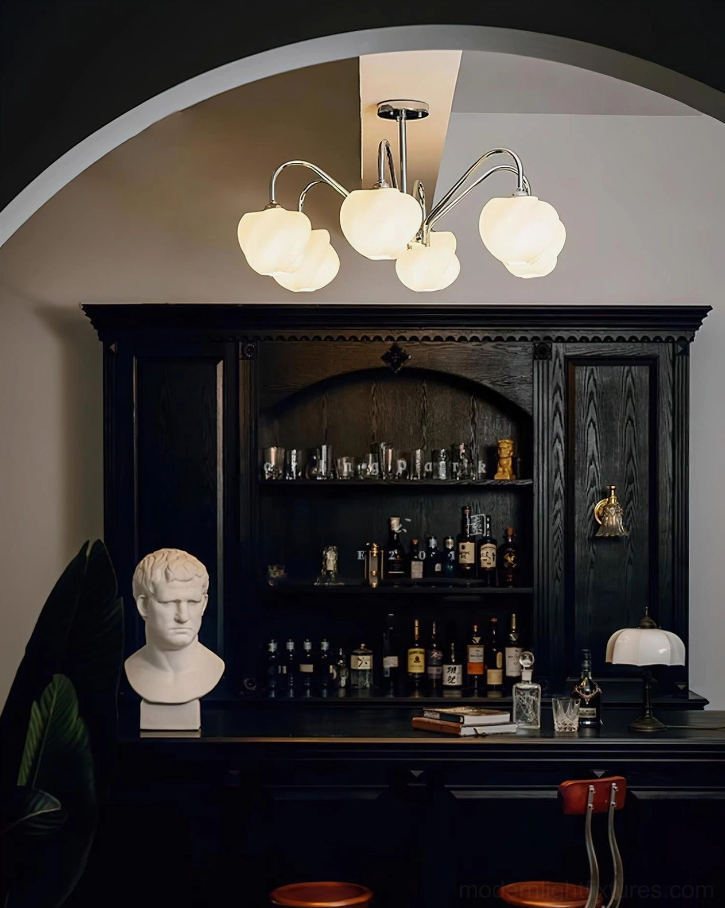 Sculptural pendant chandelier with glowing frosted shades and dark metal frame installed in classic home bar interior space