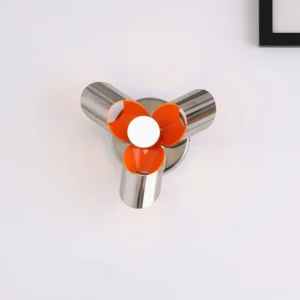 Modern Petala wall sconce with silver metal frame and orange petal accents, direct front top-down view on white wall with framed decor