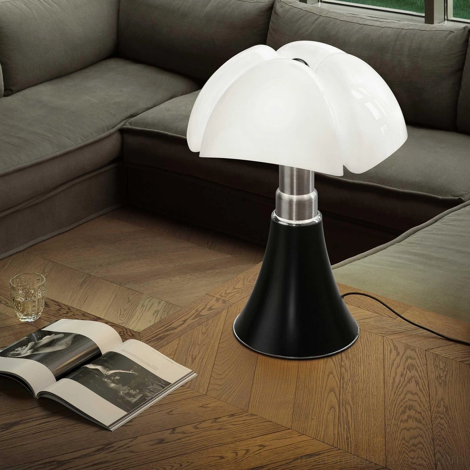 Petalica modern petal table lamp placed on wooden floor in contemporary living room with gray sofa and minimalist decor