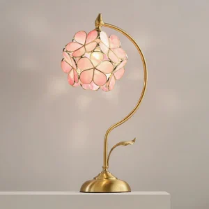 Illuminated Petalora table lamp with pink stained glass petal shade casting warm romantic glow in minimalist interior setting