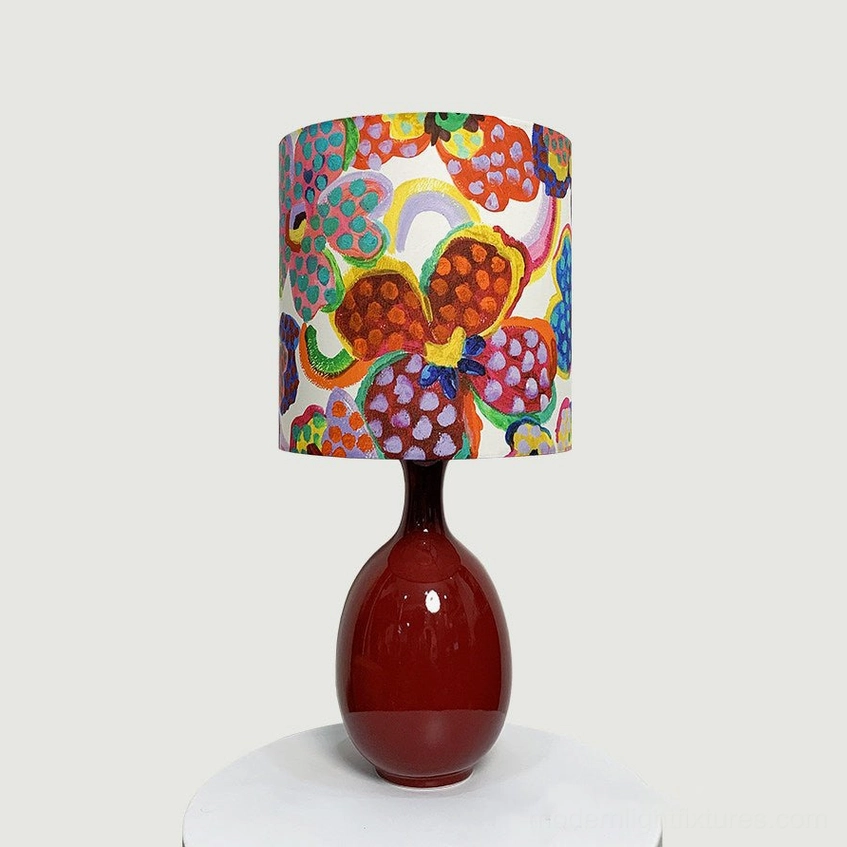 Petalyn table lamp with bright painterly floral fabric shade and oxblood red ceramic base, isolated studio photography