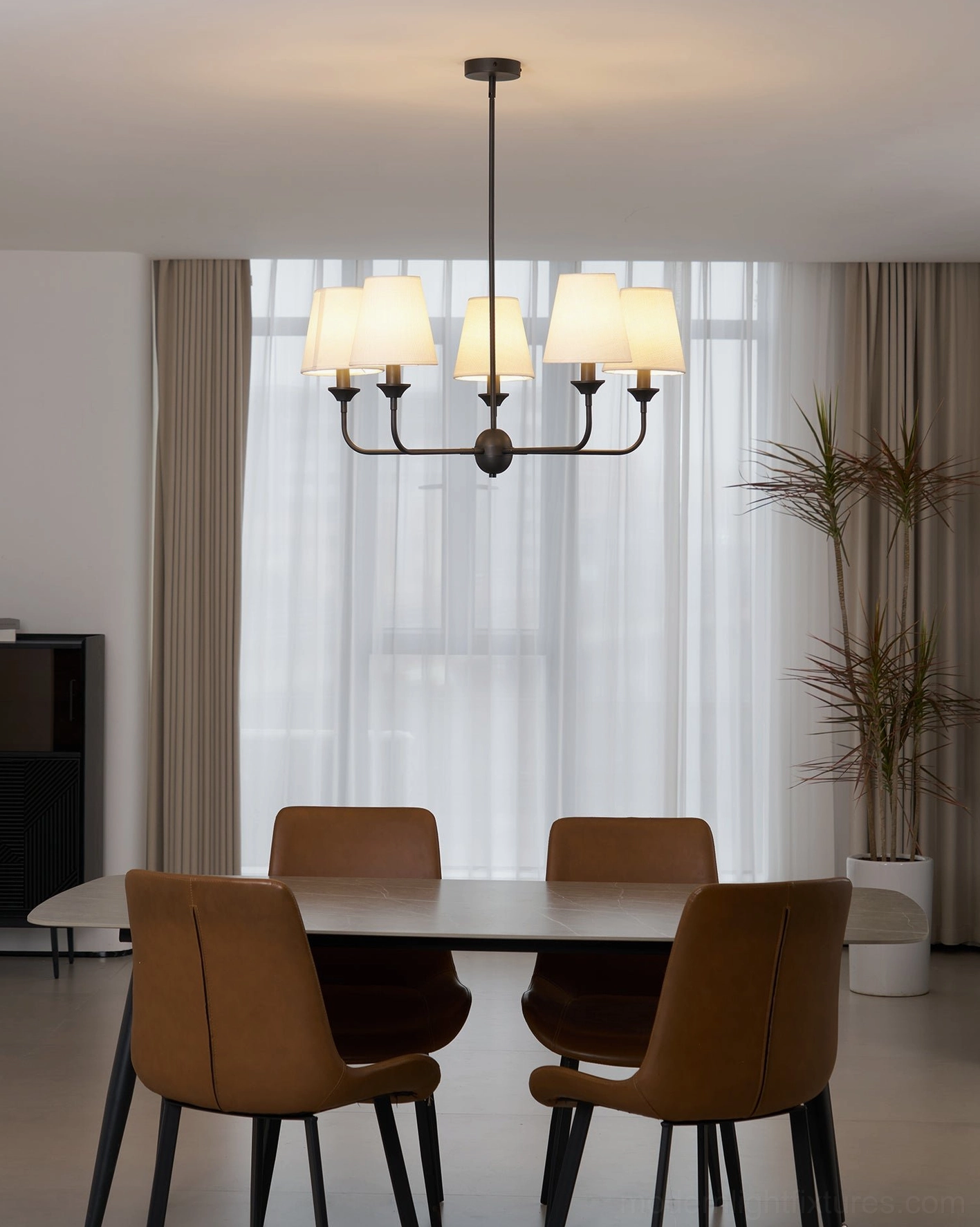 Piaf large fabric chandelier installed in modern dining room above dining table with brown chairs
