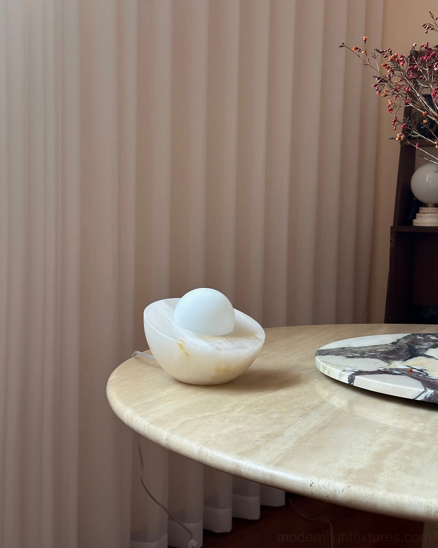 Piccola onyx marble table lamp three-quarter side view indoor setting beige curtains creamy white tone