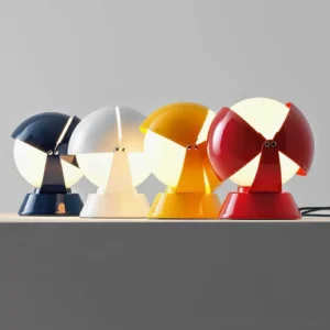 Pileino table lamp collection in four color options - navy blue, white, yellow, and red - displayed on studio shelf
