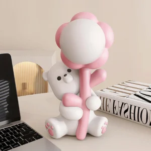 Pink bear flower desk lamp on modern home office setup with laptop and books, three-quarter angle view