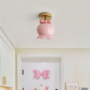 Pink glass bell ceiling light installed in white residential entryway with trimmed walls, matching decorative door bow, showcasing fixture in home setting