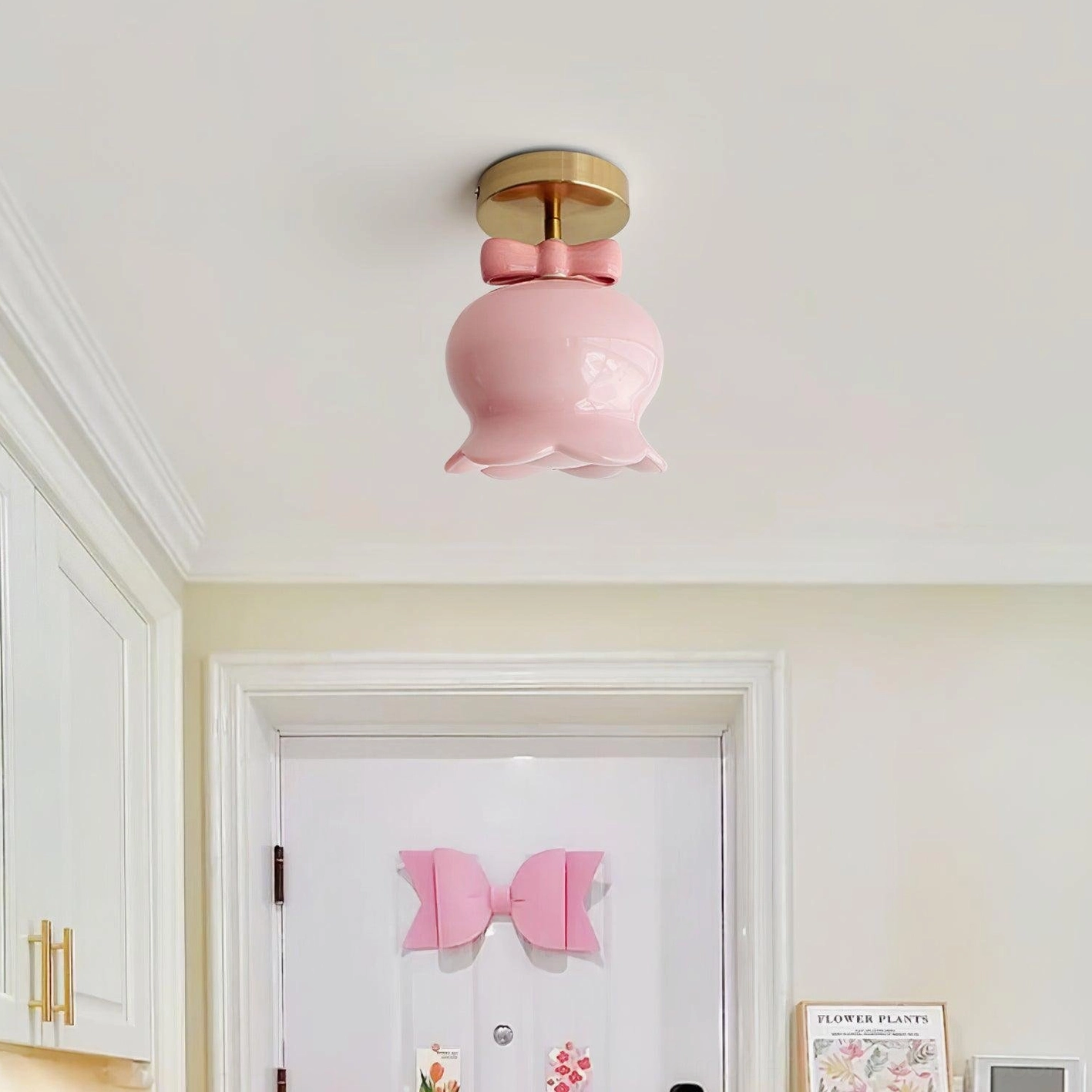 Pink glass bell ceiling light installed in white residential entryway with trimmed walls, matching decorative door bow, showcasing fixture in home setting