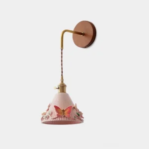 Pink butterfly ceramic wall sconce with 3D sculpted butterfly details and ribbed cone shade, front studio view