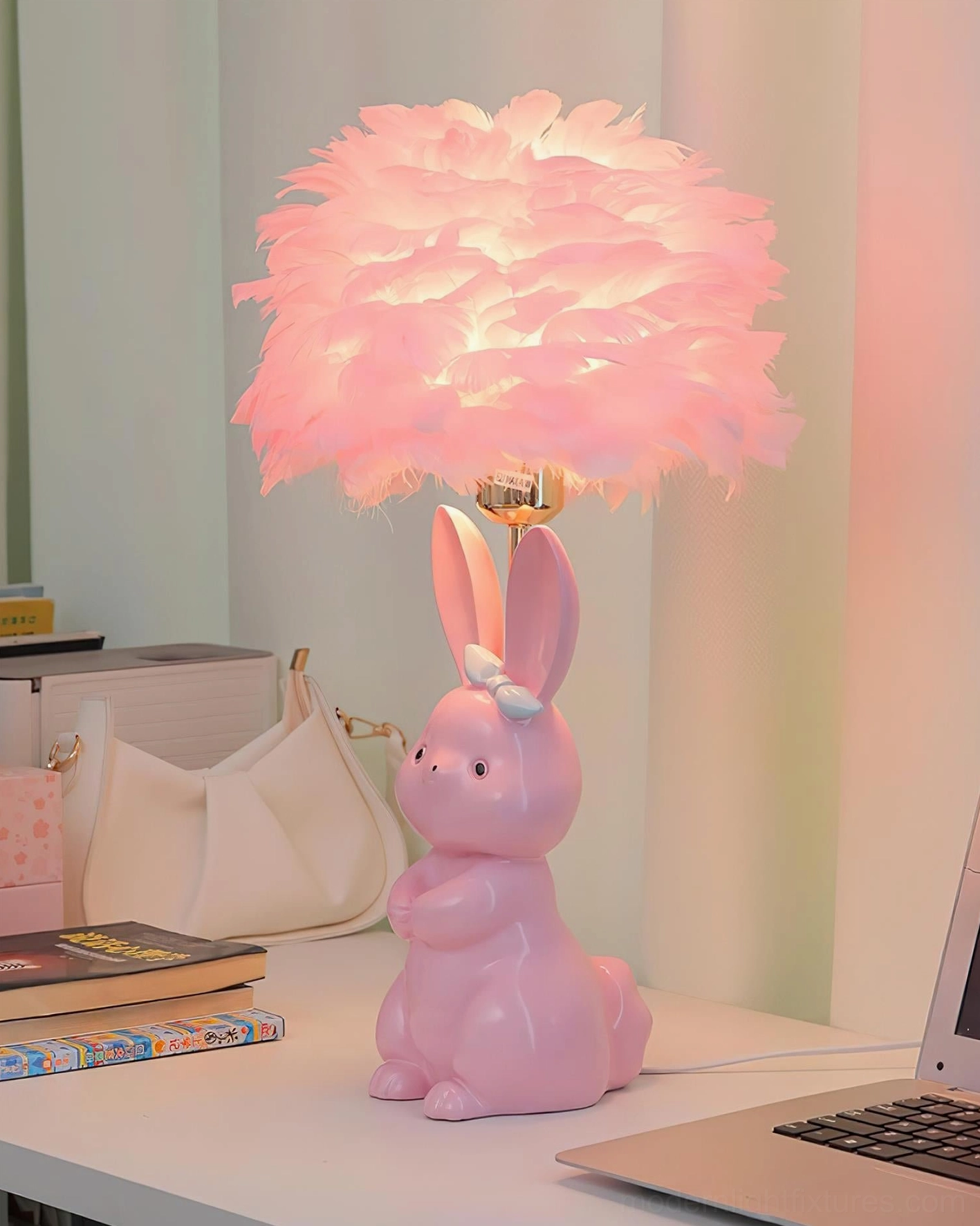 Pink ceramic bunny table lamp with lit pink feather shade and white bow on home desk - angled lighting view