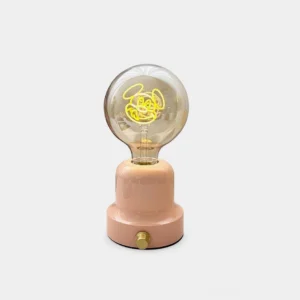 Blush pink ceramic whimsical cartoon table lamp with integrated LED and warm white glow on studio backdrop