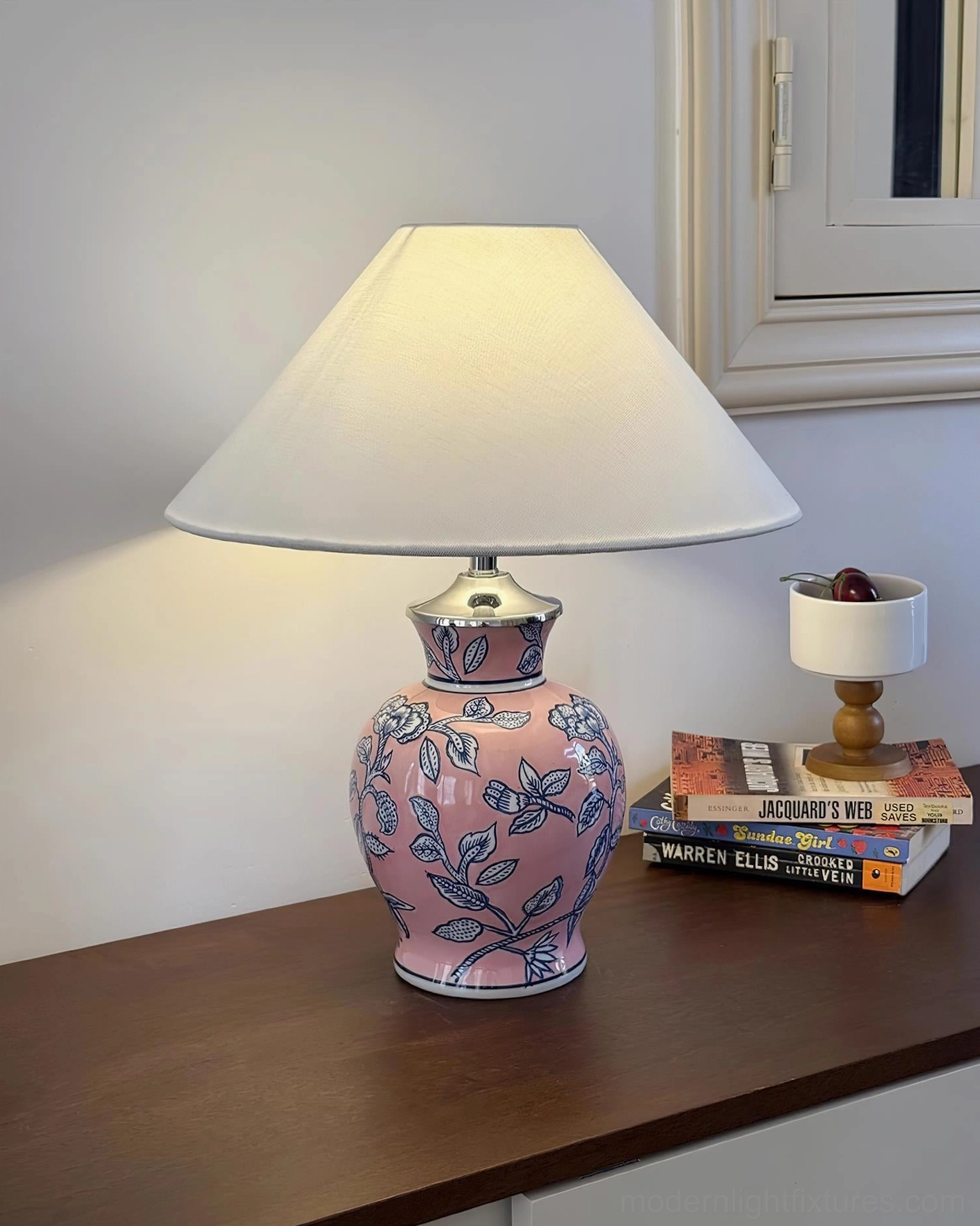 Pink ceramic floral table lamp with blue botanical pattern, console table with books and candle modern decor