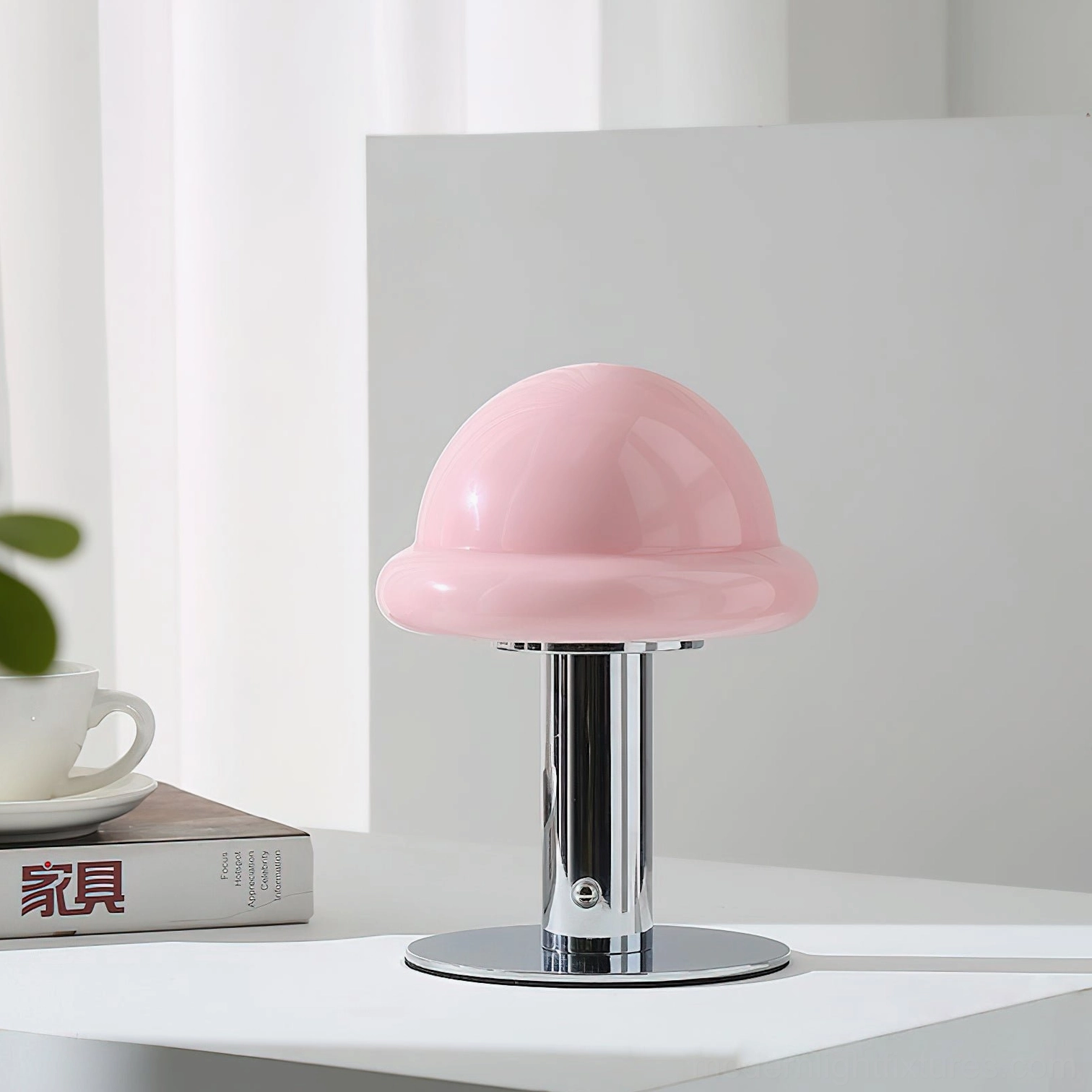 Pink chrome mushroom portable table lamp with polished metal base on white desk with books and coffee set