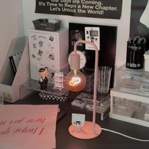 Modern pink heart lamp on home office desk with stationery and storage organizers, contemporary workspace lighting setup