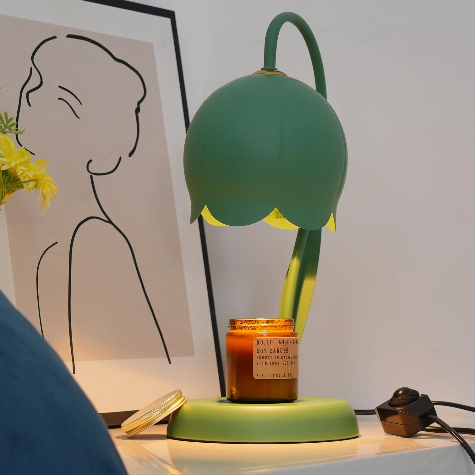Pink lily candle warmer lamp illuminated in bedroom setting creating warm ambient light and fragrance