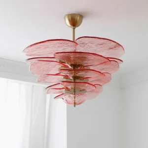 Pink lilypad glass chandelier installed in bright bedroom with sheer curtains creating soft ambient lighting
