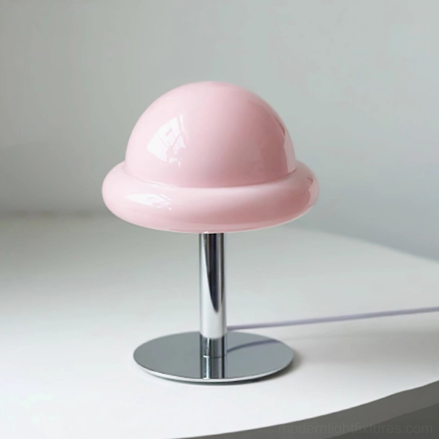 Pink glossy mushroom glass table lamp on white background with elegant chrome base