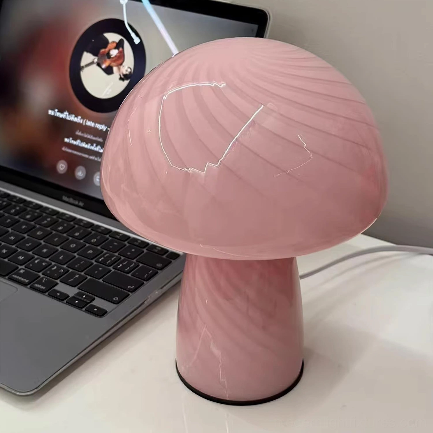 Pink glossy striped mushroom glass table lamp close-up front view in home office workspace
