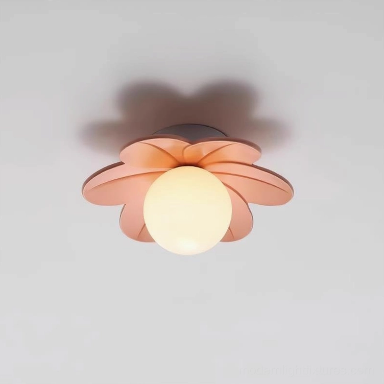 Blush pink resin petal ceiling fixture with glowing frosted glass diffuser and overhead shadow detail