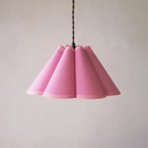 Pink pleated fabric pendant lamp showing textured conical design, minimalist wall setting