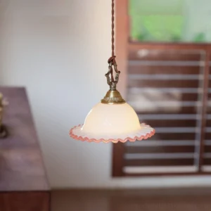 Close-up detail of pink ruffled glass rim and frosted milk glass dome with twisted brown fabric cord