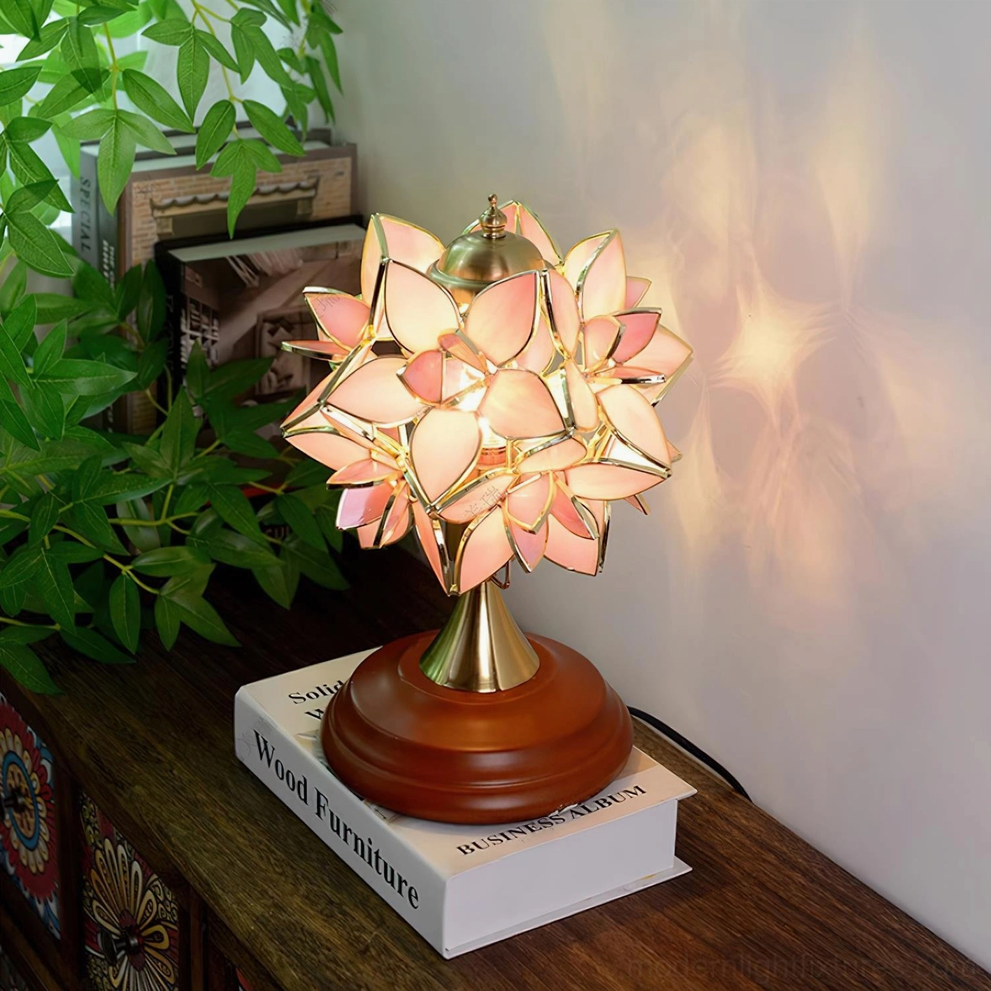 Pink petal Tiffany table lamp oblique view with warm glow on wooden side table vintage decor