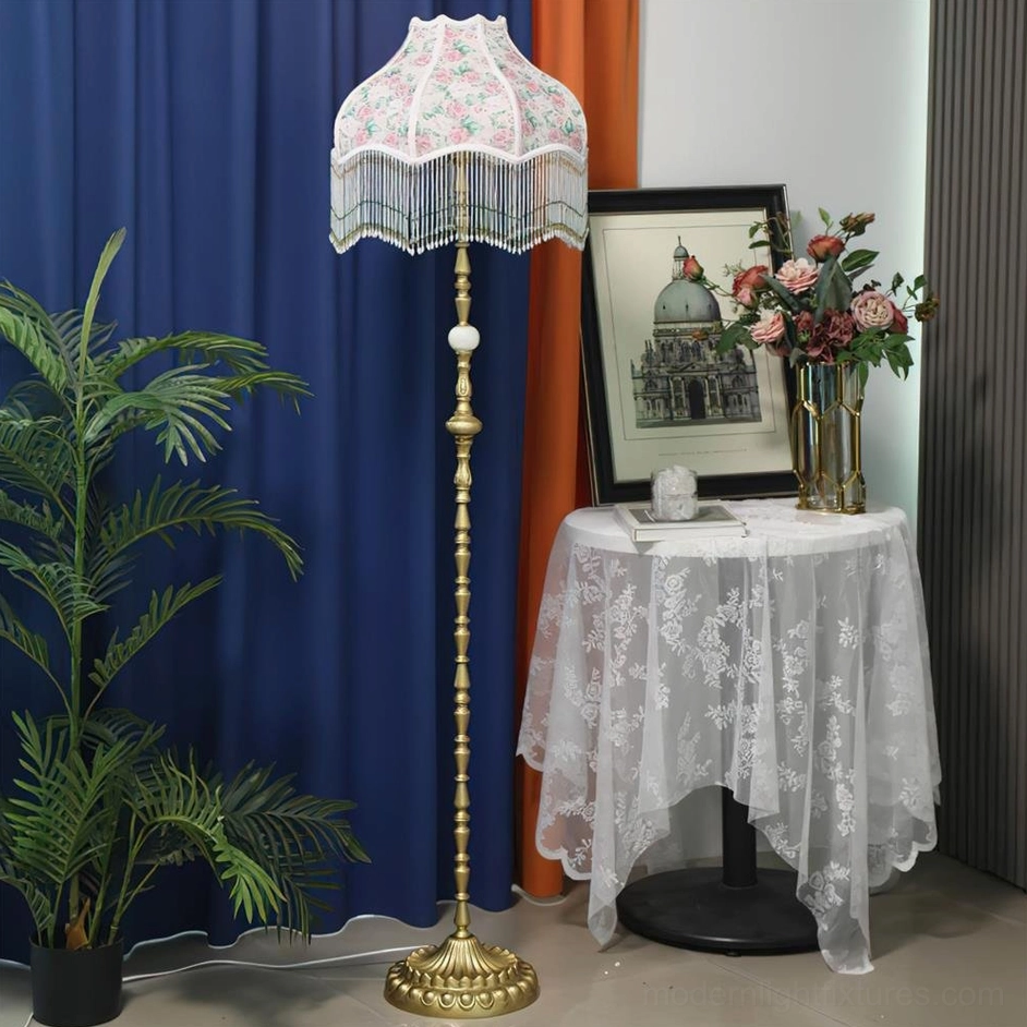 Pink Victorian floor lamp with scalloped floral shade and gold base near potted plant