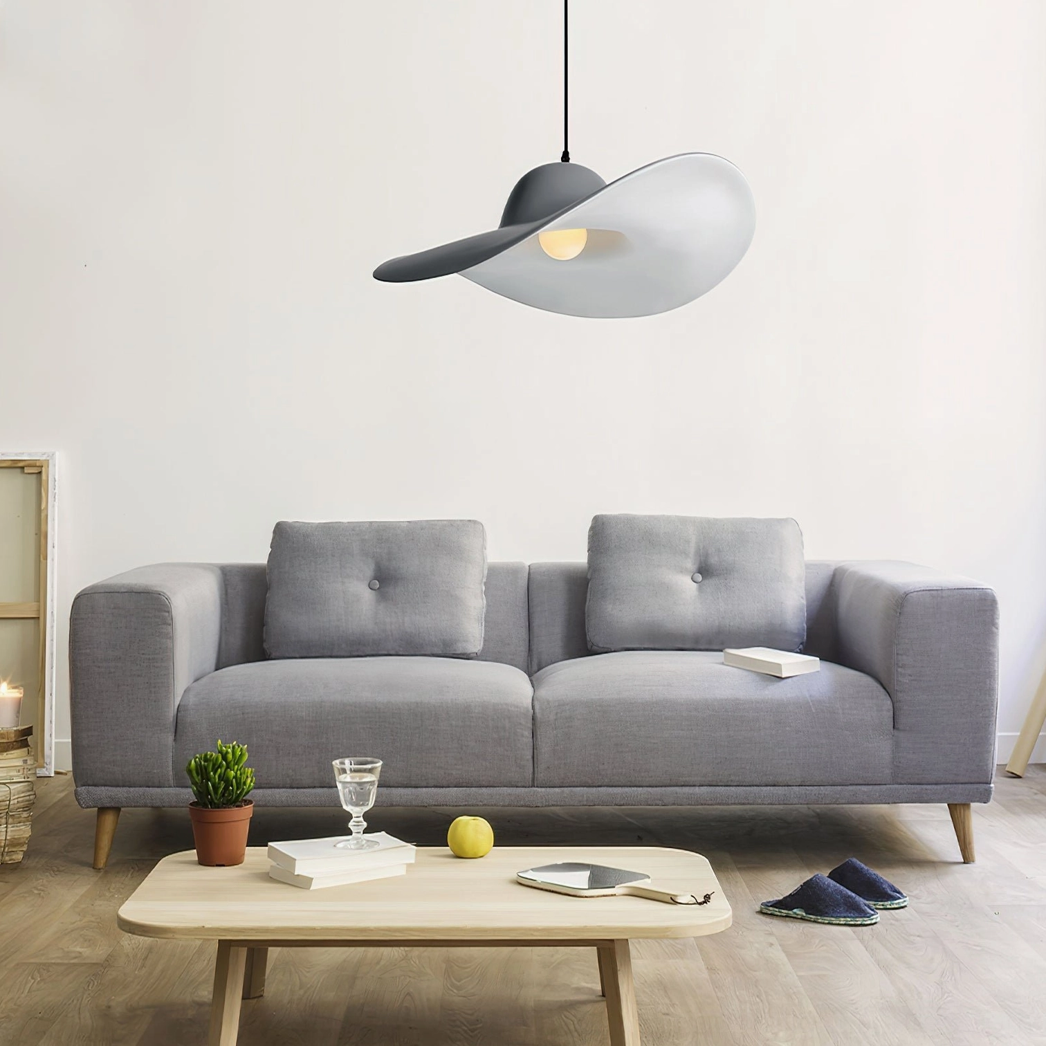 Single Piuma light gray pendant fixture in Nordic living room with sofa - modern sculptural resin design