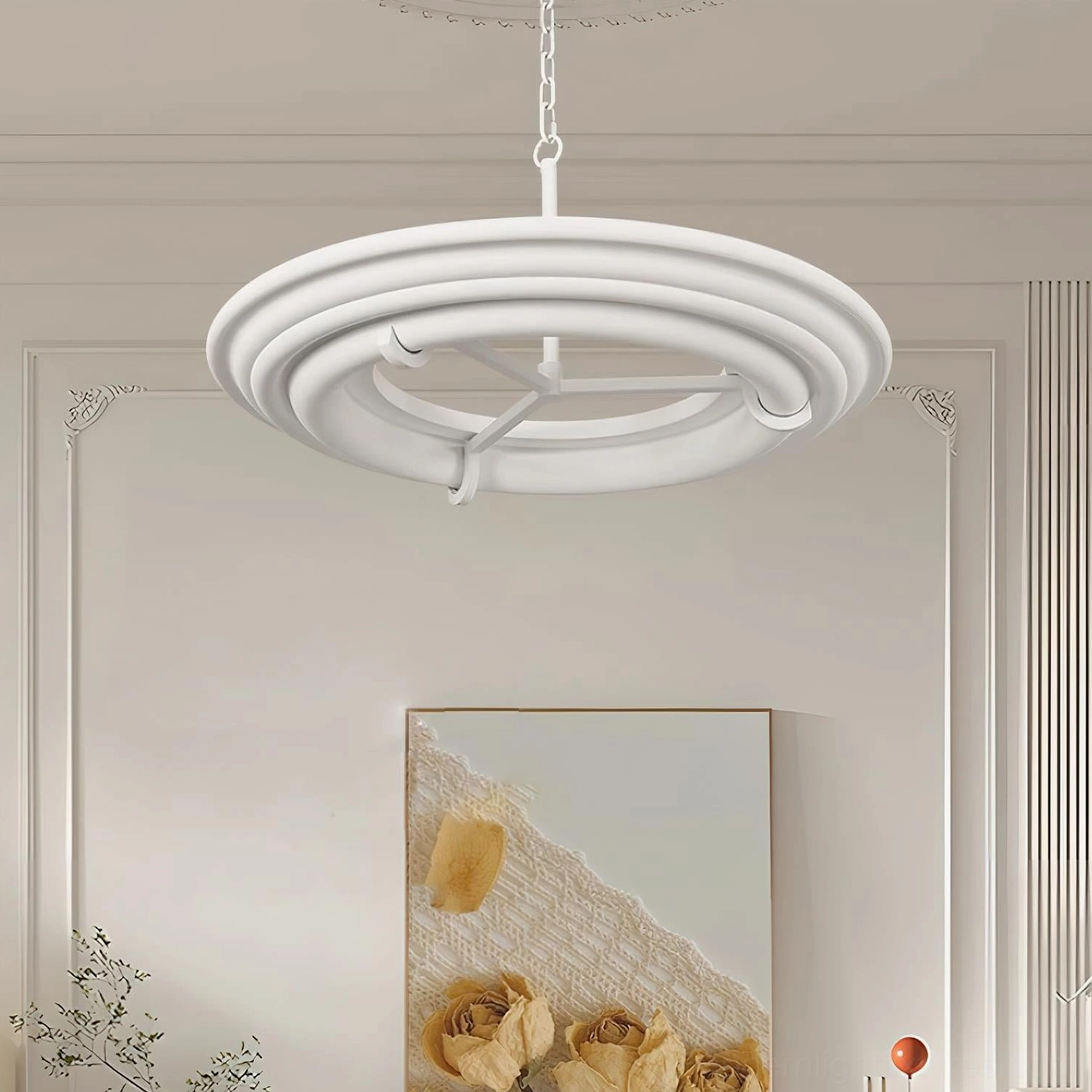Modern white plaster chandelier hanging in residential living room with wall paneling and artwork