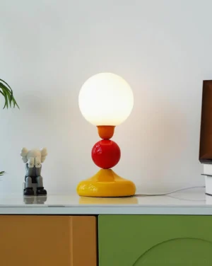 Colorful Playdot sphere table lamp displayed on side cabinet with decorative figurines and white background