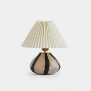 Pleated fabric table lamp with clear glass base, front view on white background showing textured shade design