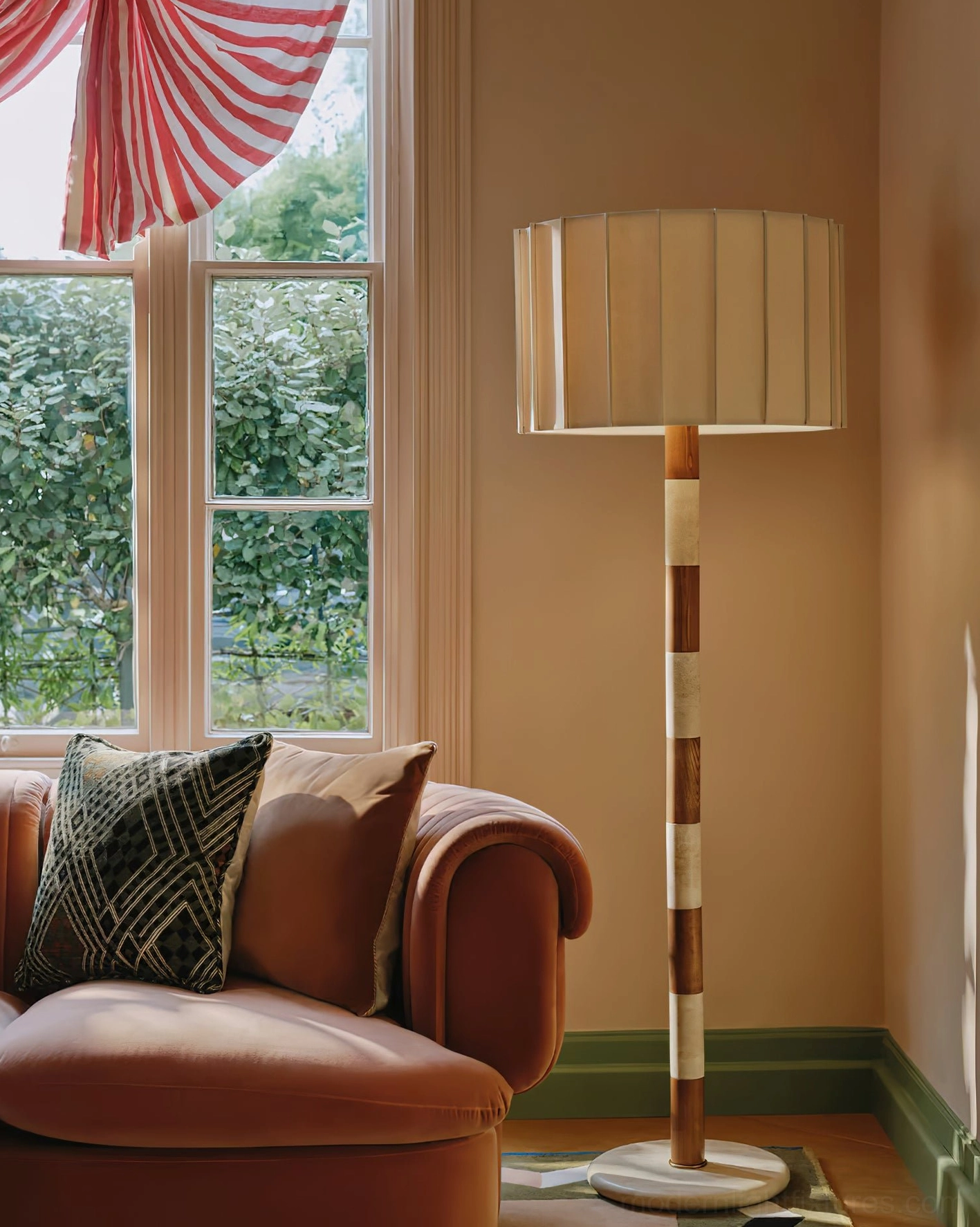 Sculptural pleated grove floor lamp three-quarter view beside brown leather sofa in cozy vintage living room with earth tone palette