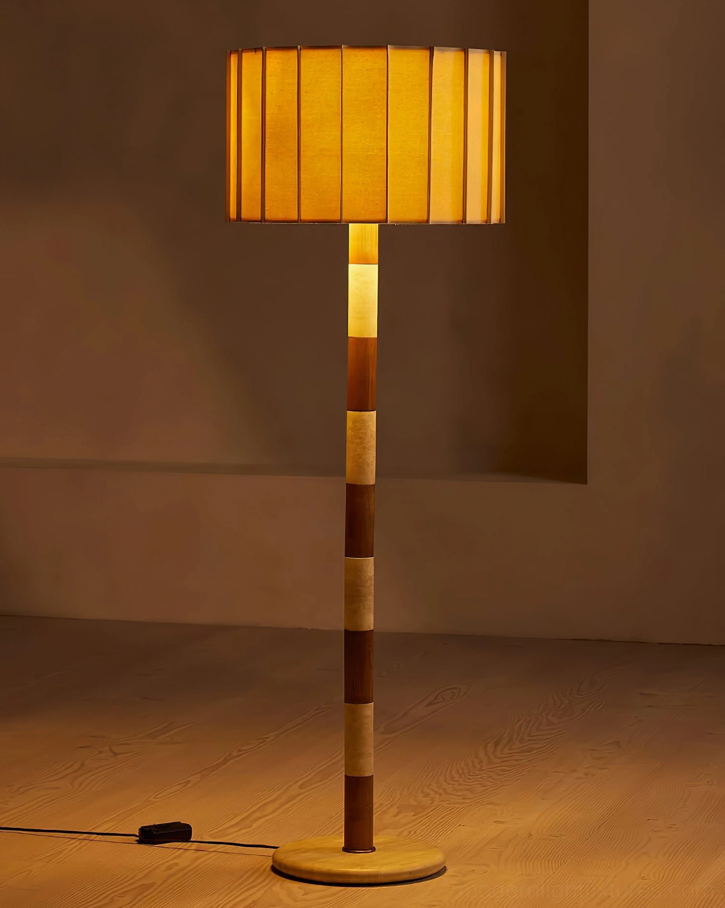 Illuminated pleated grove floor lamp with warm amber glow in dimly lit interior, showcasing the soft light diffusion through the pleated shade