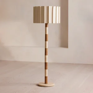 Modern pleated floor lamp in minimalist living room with light wood flooring, two-tone striped travertine and walnut column, warm neutral aesthetic
