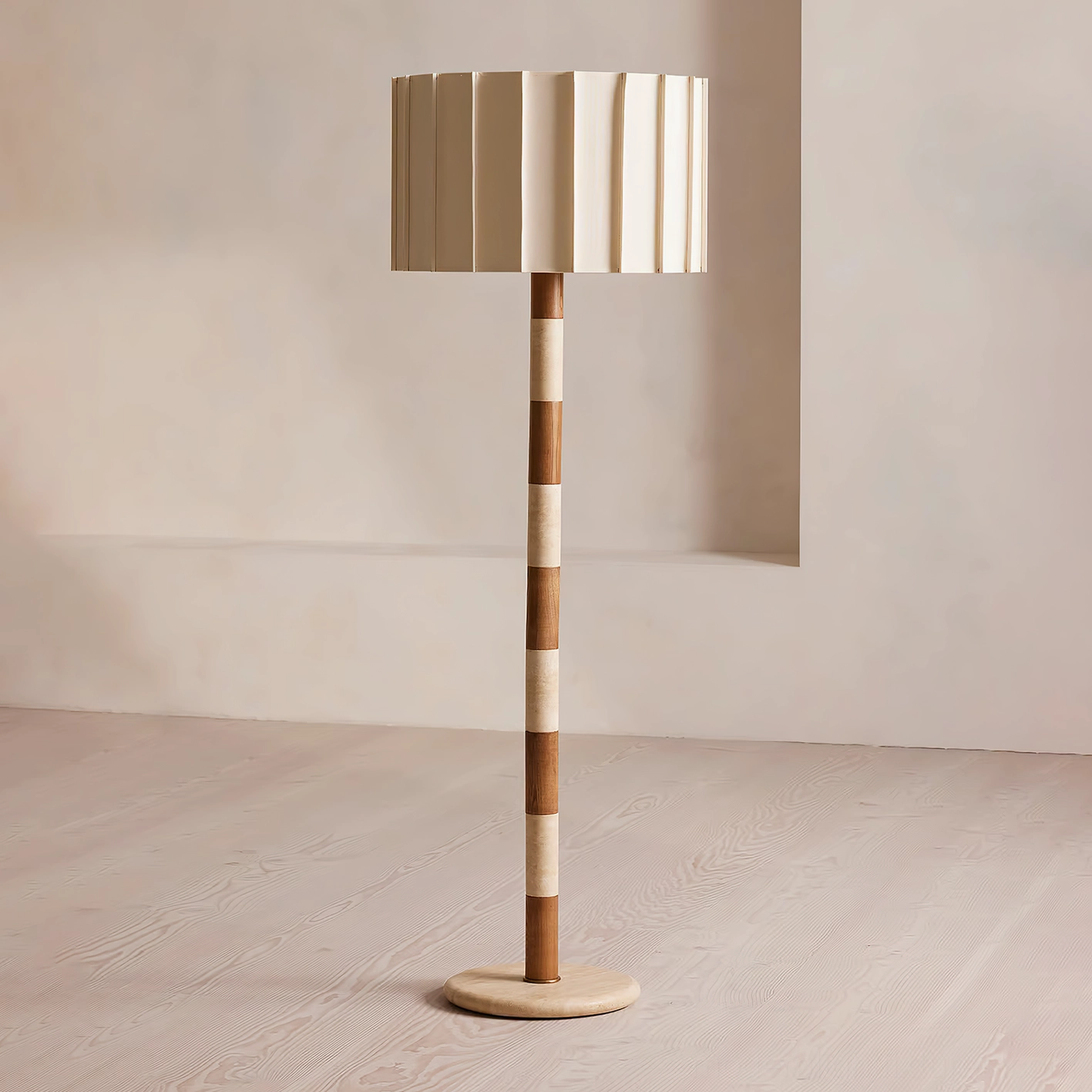 Modern pleated floor lamp in minimalist living room with light wood flooring, two-tone striped travertine and walnut column, warm neutral aesthetic