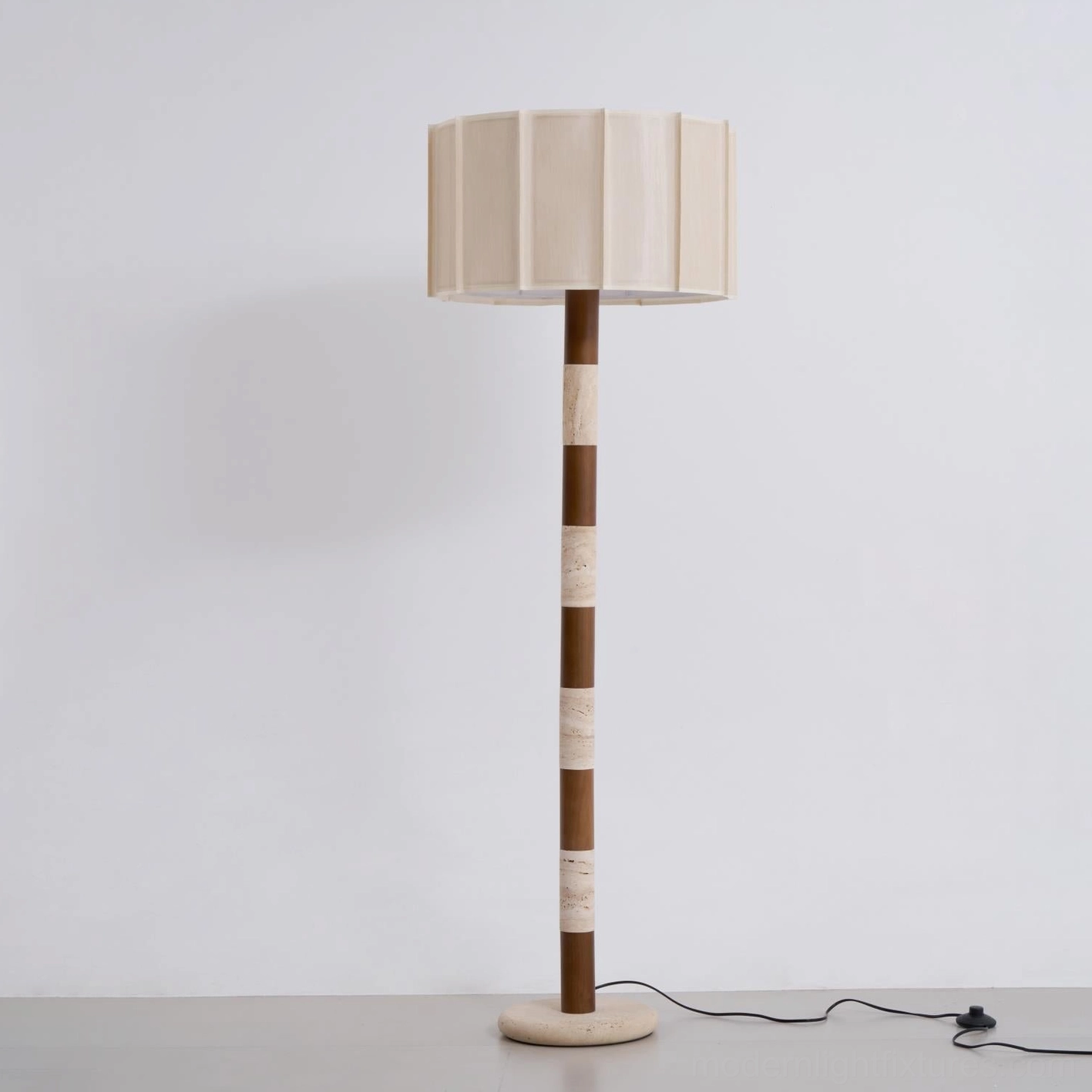Pleated grove floor lamp front view in refined interior design setting with travertine body and pleated shade creating architectural vertical presence